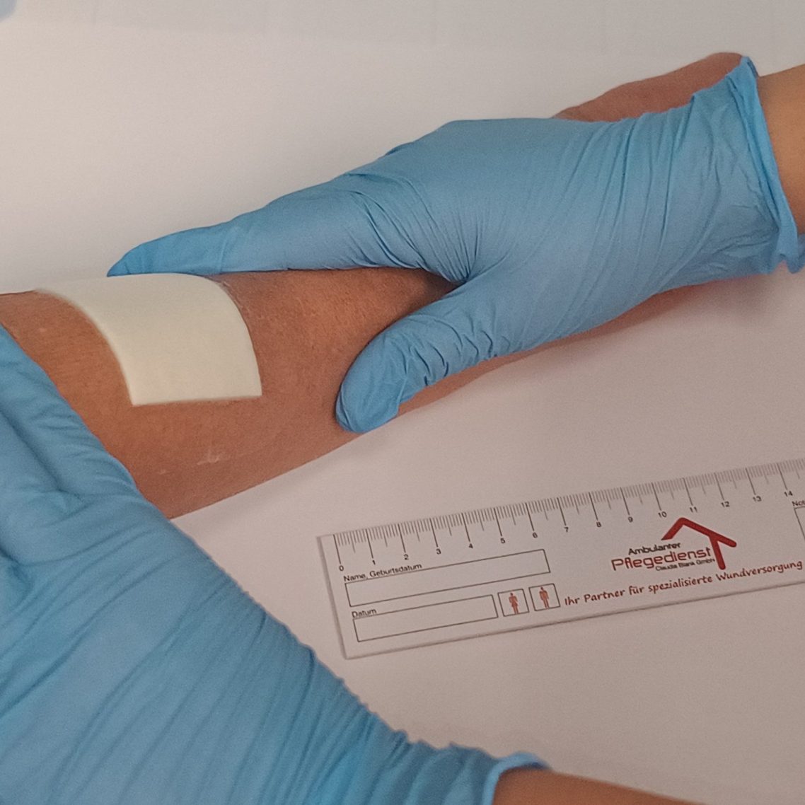 Wundversorgung Ein Pflaster wird auf einen Arm geklebt